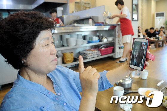 본문 이미지 - 20일 브라질 리우 올림픽 태권도 여자 67㎏급에서 금메달을 딴 오혜리(28·춘천시청) 선수의 어머니 심은자씨(57)가 응원 후 집 근처 식당에서 점심식사를 하던 중 오 선수와 영상통화를 하고 있다. 이날 오혜리는 세계태권도연맹(WTF) 올림픽 랭킹 세계 1위 하비 니아레(프랑스)를 결승에서 물리치고 금메달을 따냈다. 2016.8.20/뉴스1 ⓒ News1 서근영 기자