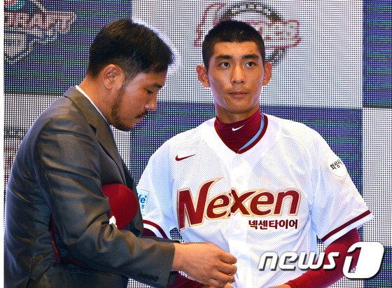 본문 이미지 -  '2017 KBO 신인 드래프트 행사'에서 넥센 히어로즈에 1차 지명된 이정후가 고형욱 넥센 단장(당시 스카우트 팀장)에게 유니폼을 전달받고 있다. . 2016.8.22/뉴스1 ⓒ News1 최현규 기자