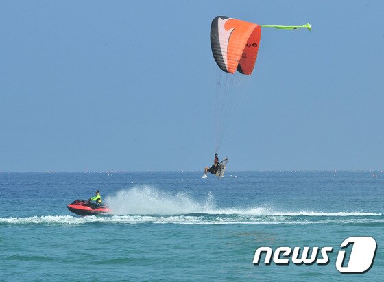 본문 이미지 - 경북 영덕군 병곡면 고래불해수욕장에서 한국재난구조단 경북지사 모터패러글라이드와 플라이보드가 물놀이 안전사고 예방 비행을 하고 있다./뉴스1