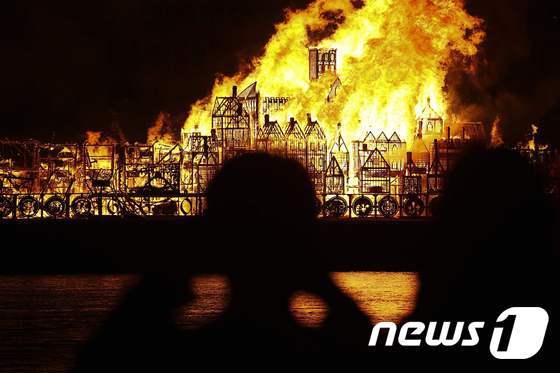 본문 이미지 - 4일(현지시간) 1666년 런던 대화재를 재현하기 위해 템스강변에 설치된 거대한 목조물이 불에 타는 모습을 시민들이 카메라에 담고 있다. ⓒ AFP=뉴스1