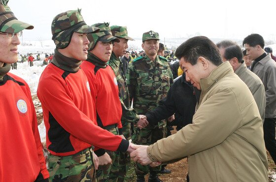 본문 이미지 - 2006년 1월 폭설 피해현장 복구에 참여한 군장병의 손을 잡아주는 노대통령ⓒ 장철영