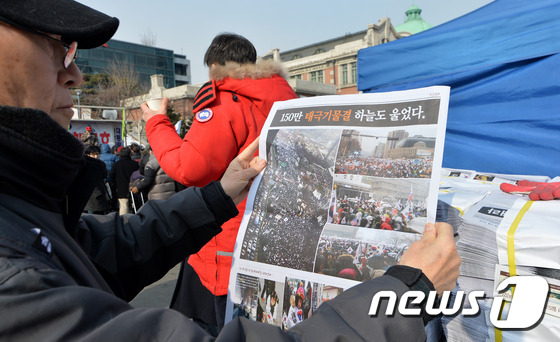 '탄핵기각' 신문보는 보수단체 회원