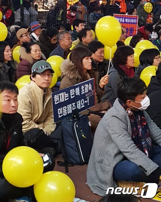 본문 이미지 - 9차 촛불집회에 참석한 시민이 조속한 탄핵을 요구하는 피켓을 들고 있다ⓒ News1