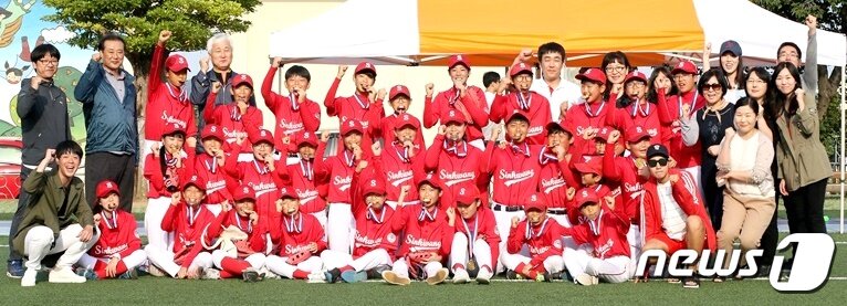 본문 이미지 - 제주도교육감배 전도학교스포츠클럽 티볼종목에서 우승을 차지한 신광초등학교 티볼부가 기념사진을 찍고 있다.  가장 아랫줄 왼쪽 끝에서 화이팅을 외치고 있는 남성이 티볼부를 이끌고 있는 김민기 교사다. 2017.10.17/뉴스1 ⓒ News1