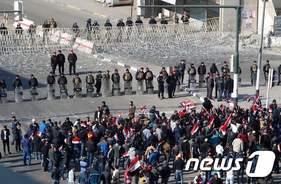본문 이미지 - 이라크 보안군이 11일(현지시간) 시위대 앞에 서 있는 모습. ⓒ AFP=뉴스1