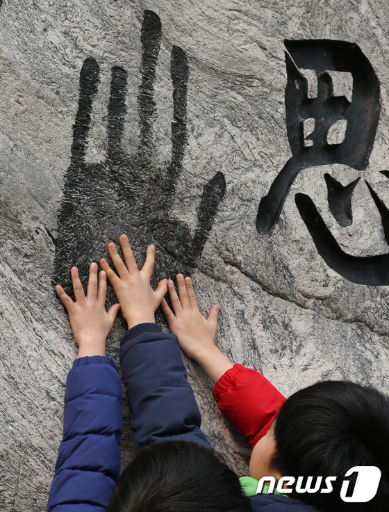 (서울=뉴스1) 허경 기자 = 3.1절인 1일 서울 중구 안중근 의사 기념관을 찾은 어린이들이 비석에 새겨진 손도장에 손을 맞대고 있다. 2017.3.1/뉴스1
