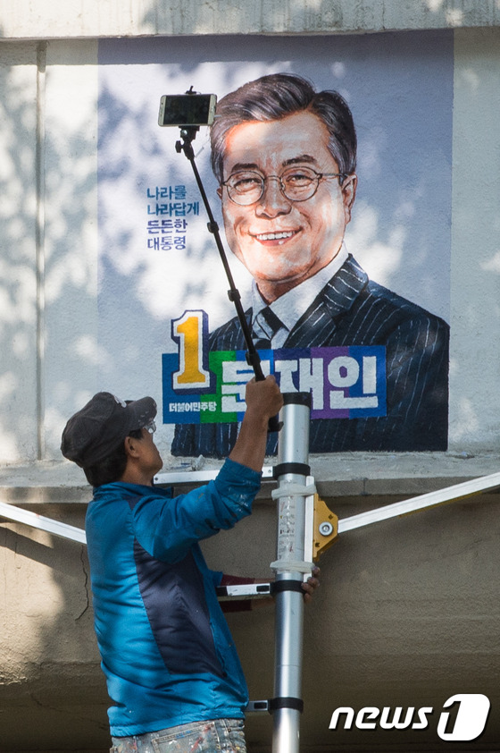 (서울=뉴스1) 유승관 기자 = 10일 서울 종로구 중앙선거관리위원회연수원에서 관계자가 제19대 문재인 대통령의 벽화를 건물 외벽에 완성한 후 촬영하고 있다. 2017.5.10/뉴 …