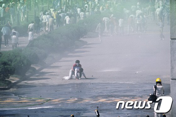 본문 이미지 - 1987년 시위 도중 경찰이 쏜 최루탄에 맞고 쓰러져 숨진 이한열 열사의 모습이 담긴 사진 2점이 공개됐다. 당시 내셔널지오그래픽 사진기자로 한국을 찾은 네이션 벤은 6월 민주항쟁 30주년을 맞아 이한열기념사업회에 이 사진을 제공했다. 사진은 1987년 6월 9일 서울 연세대학교 정문에서 경영학과 2학년생이었던 이한열 열사가 최루탄에 맞아 쓰러져 도서관학과 2학년생 이종창씨가 뒤에서 부축하고 있는 모습. (네이션 벤 제공) 2017.5.20/뉴스1