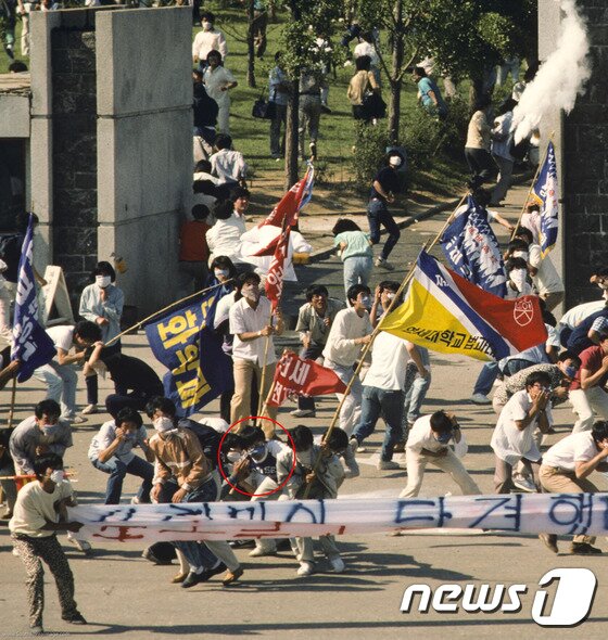 본문 이미지 - 1987년 시위 도중 경찰이 쏜 최루탄에 맞고 쓰러져 숨진 이한열 열사의 모습이 담긴 사진 2점이 공개됐다. 당시 내셔널지오그래픽 사진기자로 한국을 찾은 네이션 벤은 6월 민주항쟁 30주년을 맞아 이한열기념사업회에 이 사진을 제공했다. 사진은 1987년 6월 9일 서울 연세대학교 정문에서 경영학과 2학년생이었던 이한열 열사(현수막뒤 영문자로 ‘연세’라고 적힌 티셔츠와 파란마스크를 착용)가 피격되기 직전의 모습. (네이션 벤 제공) 2017.5.20/뉴스1