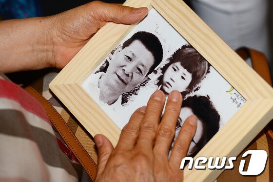 본문 이미지 - 지난 2017년 5월 열린 제11회 실종아동의 날 행사에서 실종 아동 신경하(실종당시 만5세)의 어머니인 한태순 씨가 아이 사진을 어루만지고 있다. ⓒ News1 임세영 기자