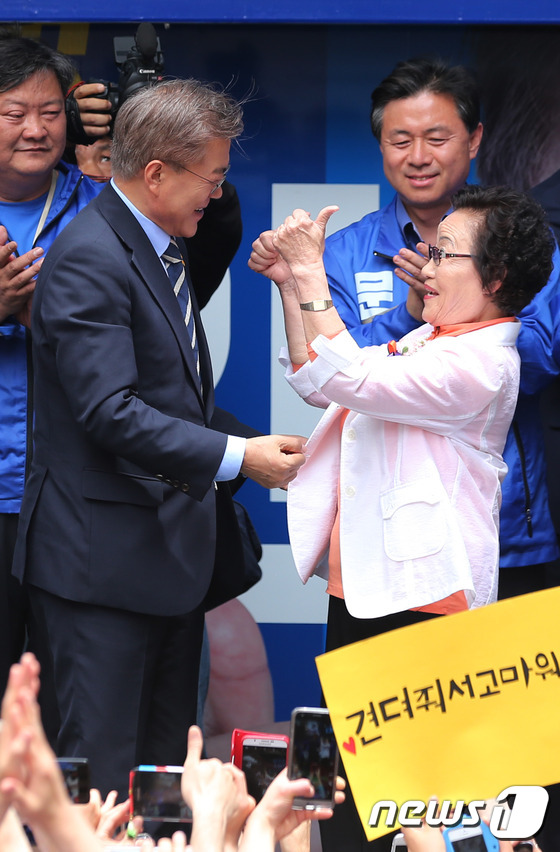 (부산=뉴스1) 박지혜 기자 = 문재인 더불어민주당 대선후보가 8일 부산 부산진구 서면에서 어버이날을 맞아 성영순 할머니에게 카네이션을 달아드린 뒤 지지를 받고 있다. 2017.5 …