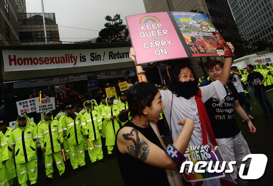 본문 이미지 - 15일 서울광장에서 열린 제 18회 퀴어문화축제에서 예수 복장을 한 참가자가 맞불집회를 벌이는 개신교 단체 회원들 앞에서 피켓 시위를 하고 있다. 성 소수자들의 권익 보호를 위해 지난 2000년 시작된 퀴어문화축제는 '나중은 없다, 지금 우리가 바꾼다'라는 슬로건 아래 진행됐다. 2017.7.15/뉴스1 ⓒ News1 오대일 기자