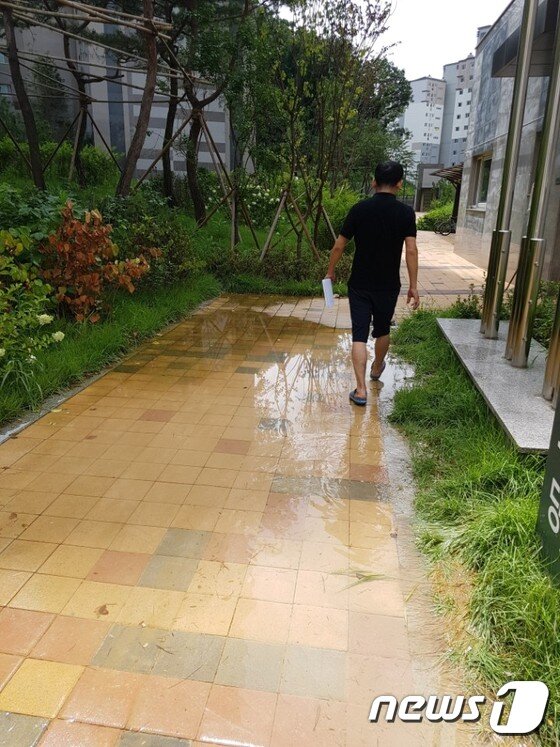 본문 이미지 - 한 입주민이 배수가 안돼 물이 고인 곳을 걸어가고 있다. 뉴스1 ⓒ News1 이윤희기자