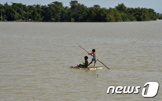본문 이미지 - 19일(현지시간) 홍수로 범람한 인도 비하르주(州)에서 어린이들이 임시 뗏목을 타고 있다. ⓒ AFP=뉴스1