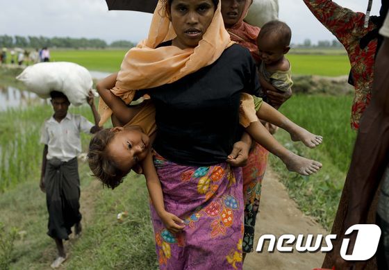 미얀마 소수민족 로힝야 난민이 아이를 업고 방글라데시 마을로 도착하고 있다. © AFP=뉴스1