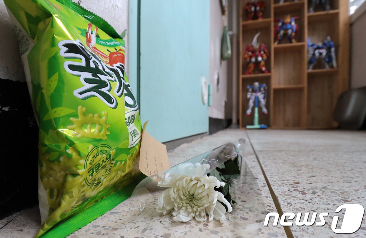 본문 이미지 - 전북 완주군에 위치한 고준희양 친부 아파트 문 앞에 '이모'라고 칭하는 사람이 적은 메모와 국화꽃이 과자와 함께 놓여 있다. 메모에는 '이모가 꺼내주지 못해서 미안해...미안해 하늘에선 괴롭고 아프고 무서운거 그런거 없이, 편안하고 따뜻하고 포근하길 기도하고 또 기도할게' 라고 적혀있다. 놓여진 꽃과 메모뒤로 고준희양 친부가 만든 모형장난감이 진열되어 있다.2018.1.4/뉴스1 ⓒ News1 문요한 기자