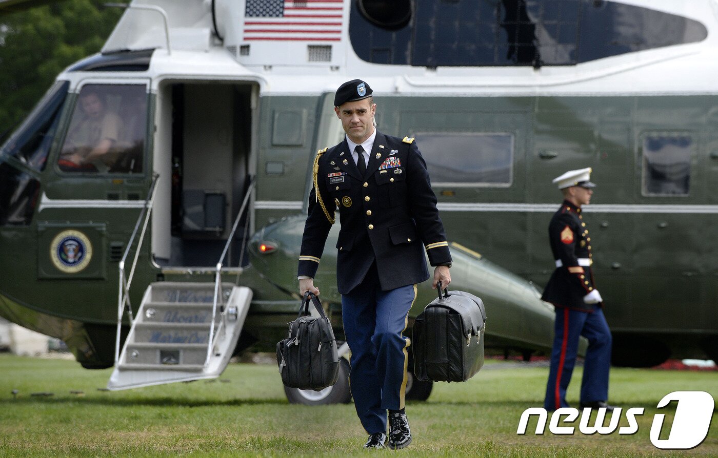 본문 이미지 - 오바마 전 미국 대통령 전용기 앞에서 미군 장교가 풋볼을 들고 이동 중이다. ⓒ AFP=뉴스1