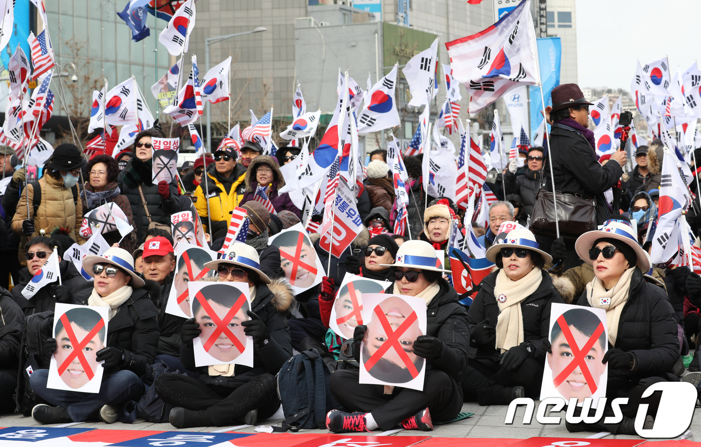 (서울=뉴스1) 신웅수 기자 = 11일 오후 서울 동대문구 동대문디자인플라자(DDP) 앞에서 대한애국당 주최로 열린 태극기집회에서 참가자들이 전일 북한 응원단이 사용한 ‘미남 가면 …