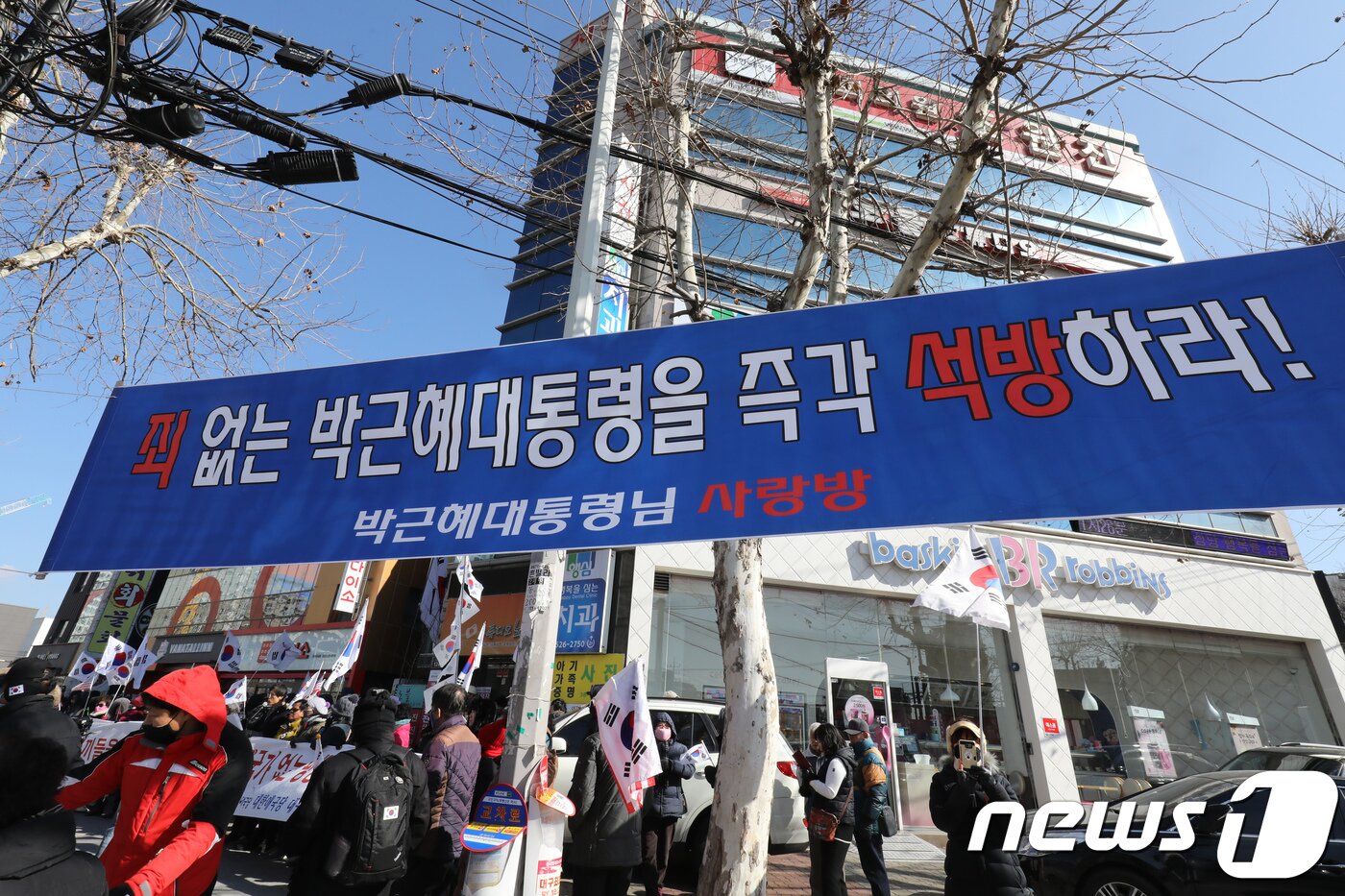 본문 이미지 - 5일 오전 대구 달서구 감삼동 조원진 대한애국당 의원 사무실 앞에서 대한애국당원과 지지자를 비롯한 보수시민단체 회원들이 ‘평양올림픽 반대’ 집회를 열고 있다. 횡단보도 앞 가로수에 박근혜 전 대통령 석방을 촉구하는 플래카드가 걸려 있다. 2018.2.5/뉴스1 ⓒ News1 공정식 기자