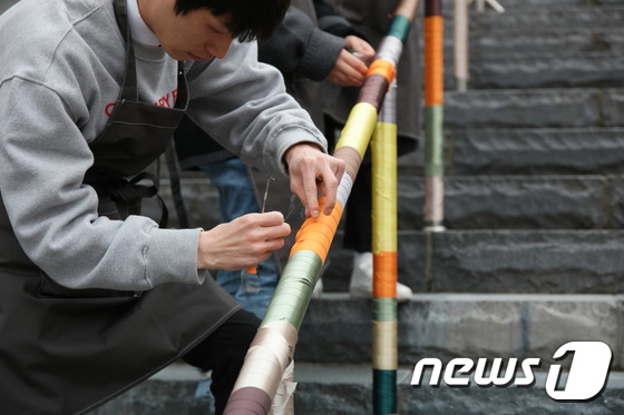 대학생 자원봉사자들이 천안 남산공원 계단 난간을 무지개색 천으로 장식하고 있다. © News1