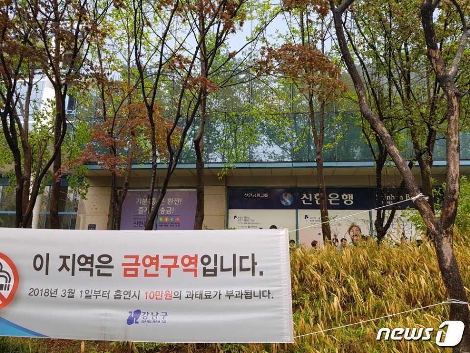 본문 이미지 - 강남구 도곡동 '금연지역'임을 알리는 현수막 뒤로 인근 직장인들이 담배를 피우고 있다. 2018.04.24 ⓒ News1이승환 기자