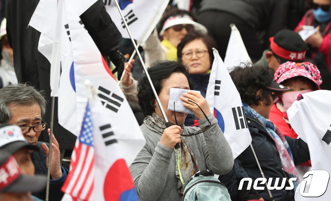 본문 이미지 - 박근혜 전 대통령 지지자가 6일 서울 서초구 법원삼거리 인근에서 집회를 이어가던 중 재판부가 박 전 대통령에게 24년형을 선고하자 울먹이고 있다. 박 전 대통령은 '비선실세' 최순실씨(62)가 실소유한 미르·K스포츠재단의 출연금 774억원을 대기업에 강제했다는 혐의(직권남용 권리행사방해·강요) 등 18개 혐의로 기소됐다. 2018.4.6/뉴스1 ⓒ News1 허경 기자