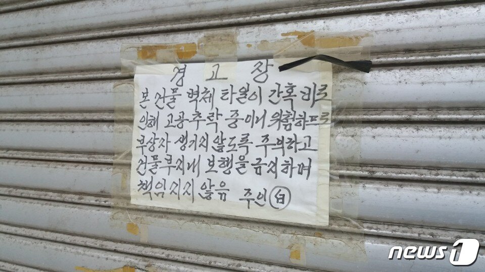 본문 이미지 - 조선소 인근 상가 건물에 경고문 모습. 외관이 떨어져 나갈 수 있으니 행인들의 주의를 당부하고 있다.ⓒ News1