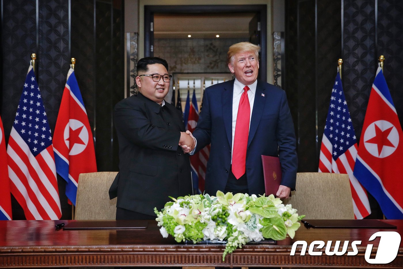 본문 이미지 - 김정은 북한 국무위원장과 도널드 트럼프 미국 대통령이 12일 싱가포르 센토사 섬 카펠라 호텔에서 북미정상회담 공동합의문에 서명을 마친 뒤 악수를 나누고 있다. (싱가포르통신정보부 제공) 2018.6.12/뉴스1