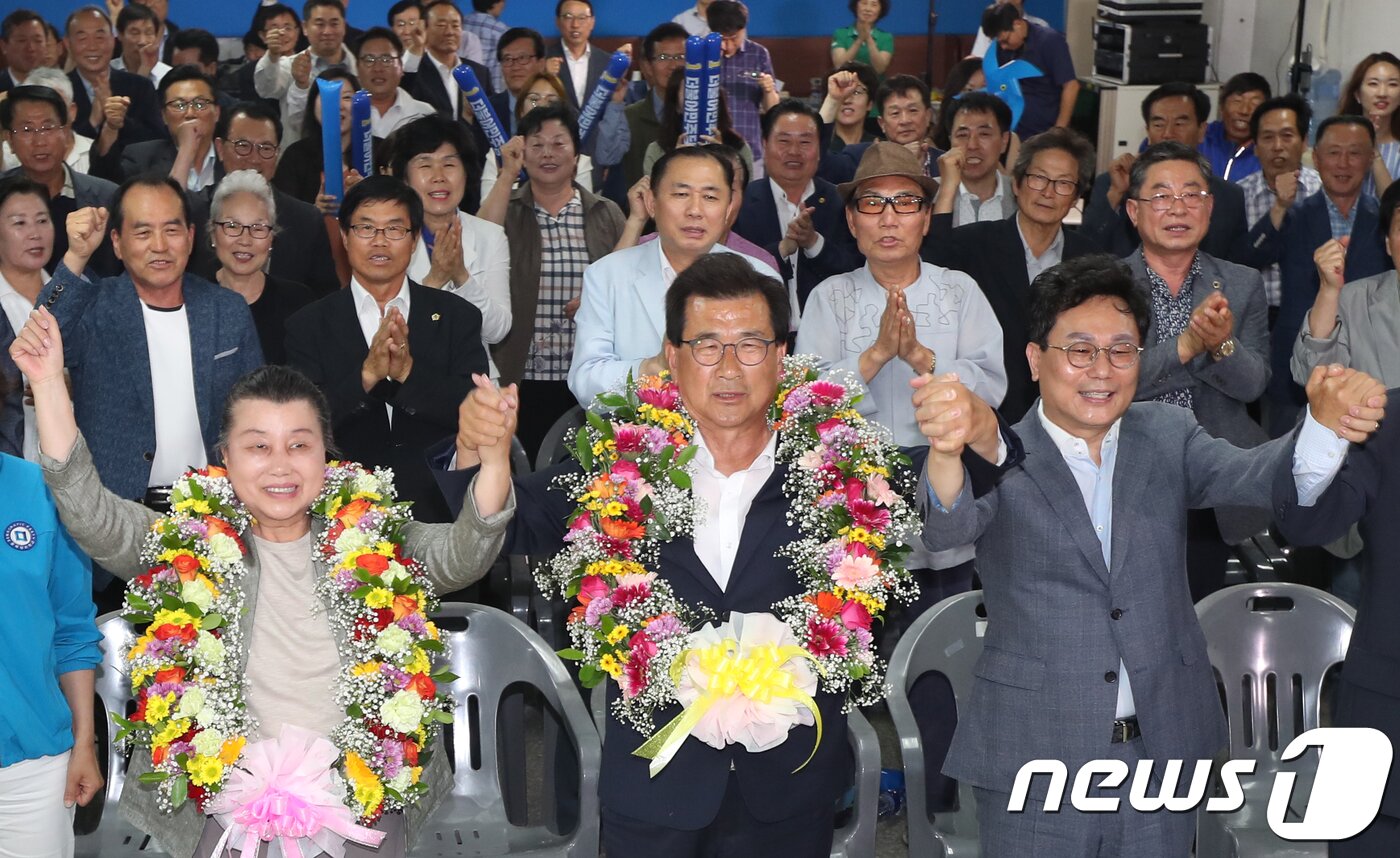 본문 이미지 - 이시종 더불어민주당 충북도지사 후보와 부인 김옥신씨가 13일 오후 충북 청주시 흥덕구 선거캠프에서 6·13 지방선거 당선이 확실시되자 꽃목걸이를 목에 걸고 손을 들고 있다.2018.6.13/뉴스1 ⓒ News1 김용빈 기자