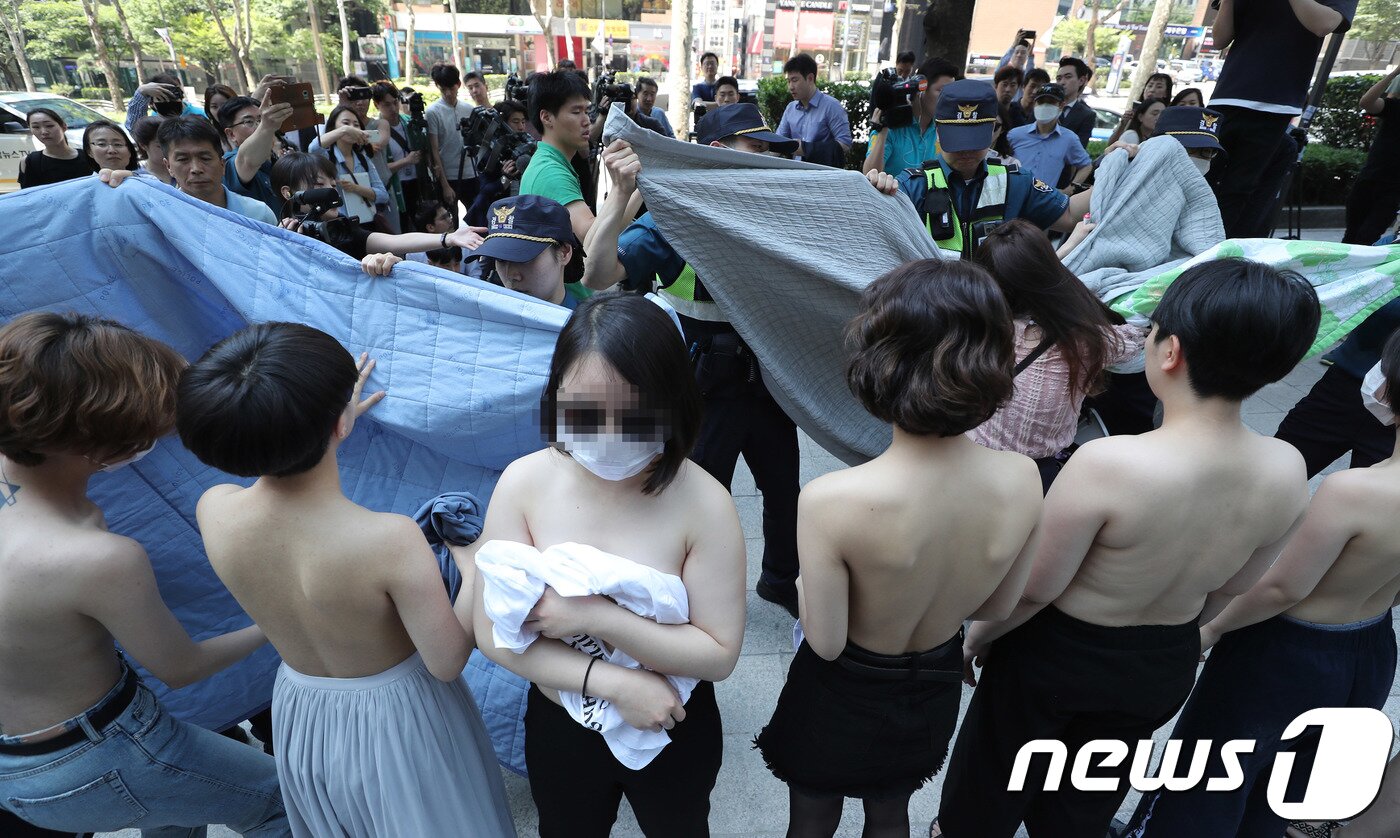 본문 이미지 - 불꽃페미액션 활동가들이 지난 2일 오후 서울 강남구 페이스북코리아 사옥 앞에서 성차별적 규정에 맞서는 상의탈의 퍼포먼스를 벌이다 경찰에게 제지 당하고 있다. 이 단체는 페이스북이 남성의 나체 사진은 제제를 가하지 않으면서 여성의 나체 사진만 삭제하는 것에 항의하기 위해 이번 시위를 진행했다. /뉴스1 ⓒ News1 이재명 기자