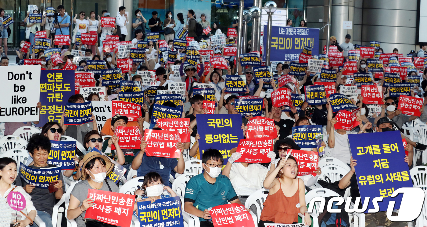 (서울=뉴스1) 황기선 기자 = 난민대책국민행동 회원들이 14일 오후 서울 광화문 동화면세점 앞에서 열린 '제주 예멘 난민수용 반대 집회'에서 손팻말을 들고 구호를 외치고 있다.이 …