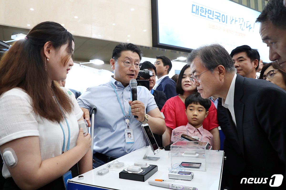 문재인 대통령이 19일 경기도 성남 분당서울대병원 헬스케어혁신파크에서 열린 의료기기 규제혁신 및 산업 성장 방안 정책 발표 행사를 마친 후 김재진 이오플로우 대표&#40;가운데&#41;로부터 당뇨치료용 인슐린 주입패치 설명을 듣고 있다. &#40;청와대 제공&#41; 2018.7.19/뉴스1