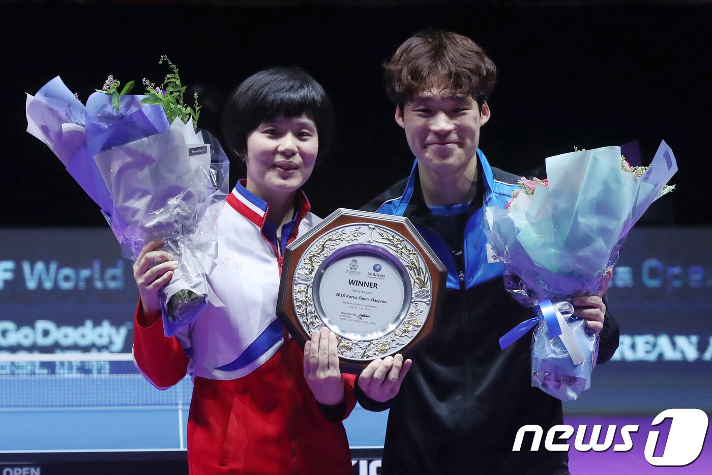 On July 21, 2018, at the Chungmu Gymnasium in Jung-gu, Daejeon, members of the inter-Korean unified team—Jang Woo-jin of South Korea and Cha Hyo-sim of North Korea—are seen smiling brightly while holding their trophy and a bouquet of flowers at the award ceremony following their 3-1 victory over the Chinese national team in the mixed doubles final of the 2018 Korea Open International Table Tennis Championships 2018.7.21 / News1