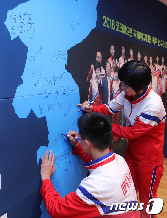 한반도 지도에 사인하는 북한 탁구선수들