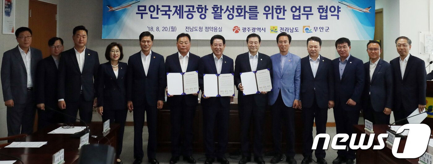본문 이미지 - 김영록(가운데) 전남도지사, 이용섭(오른쪽 여섯번째) 광주시장, 김산(왼쪽 여섯번째) 무안군수 등이 20일 오전 전남도청 정약용실에서 무안국제공항 활성화를 위한 광주 민간공항의 무안 국제공항 통합 업무협약을 체결하고 협약서를 들어보이고 있다. 2018.8.20/뉴스1 ⓒ News1