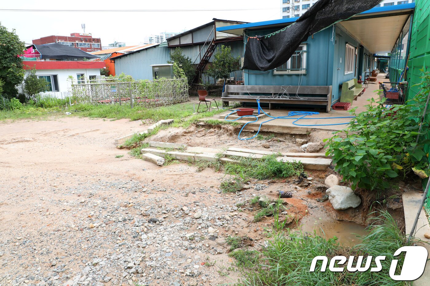 본문 이미지 - 속초 시립테니스장(오른쪽)과 침수 피해주택(왼쪽 첫번째) 사이에 설치된 컨테이너. ⓒ News1 고재교 기자