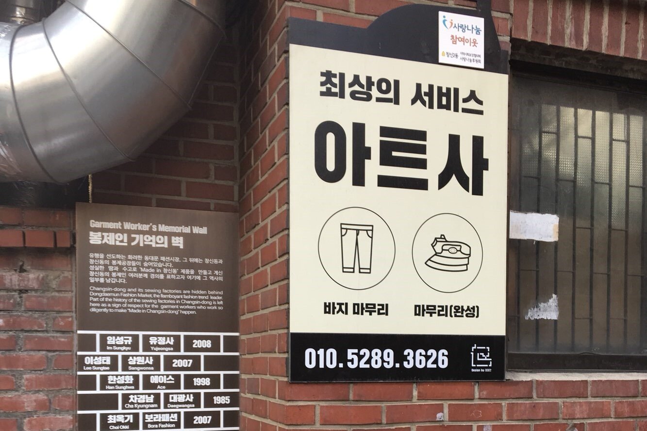 본문 이미지 -  봉제거리에 최신 트렌드에 맞는 홍보 푯말이 걸려 있다.