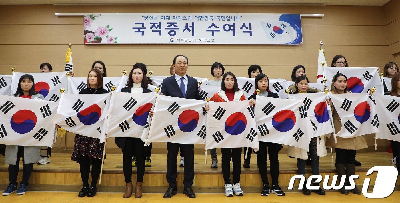 본문 이미지 - 29일 오후 제주출입국·외국인청 대강당에서 '제주 첫 국적증서 수여식'을 마친 뒤 귀화자 20명과 김도균 제주출입국청장이 함께 기념사진을 찍고 있다. 2019.01.29/뉴스1 ⓒ 뉴스1 안서연 기자