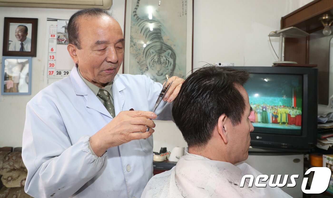 본문 이미지 - 대전 동구 소제동 문을 연지 50여년 된 대창미용원 이종완 이발사(82)가 손님의 머리를 자르고 있다. 이 씨는 “10여 년 전부터 재개발 얘기가 나와서 개발이 시작되면 나도 가위를 놓아야지 싶었다. 그렇게 하루하루 기다리다 보니 어느덧 80이 넘어서도 가위를 놓지 못하고 있다”고 말했다. 2019.1.4/뉴스1 ⓒ News1 주기철 기자