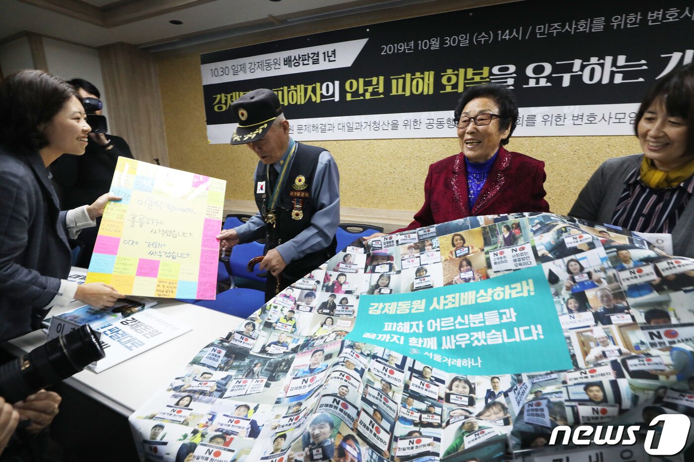 본문 이미지 - 강제징용 피해자 이춘식 할아버지와 양금덕 할머니가 30일 오후 서울 서초동 민주사회를위한변호사모임 대회의실에서 열린 '10·30 일제 강제동원 배상판결 1년' 강제동원 피해자의 인권 피해회복을 요구하는 기자회견을 마친 후 응원 메시지를 선물로 받고 있다 2019.10.30/뉴스1 ⓒ News1 이재명 기자