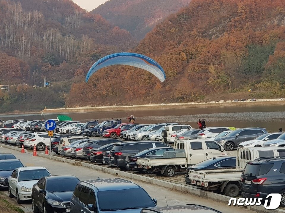 본문 이미지 - 주말을 맞아 관광객들의 차량으로 크게 붐비는 충북 단양군 단양읍 하상주차장과 근접한 하천부지에 패러글라이더가 위험천만하게 착륙하고 있다. .2019.11.11/ⓒ 뉴스1 조영석기자