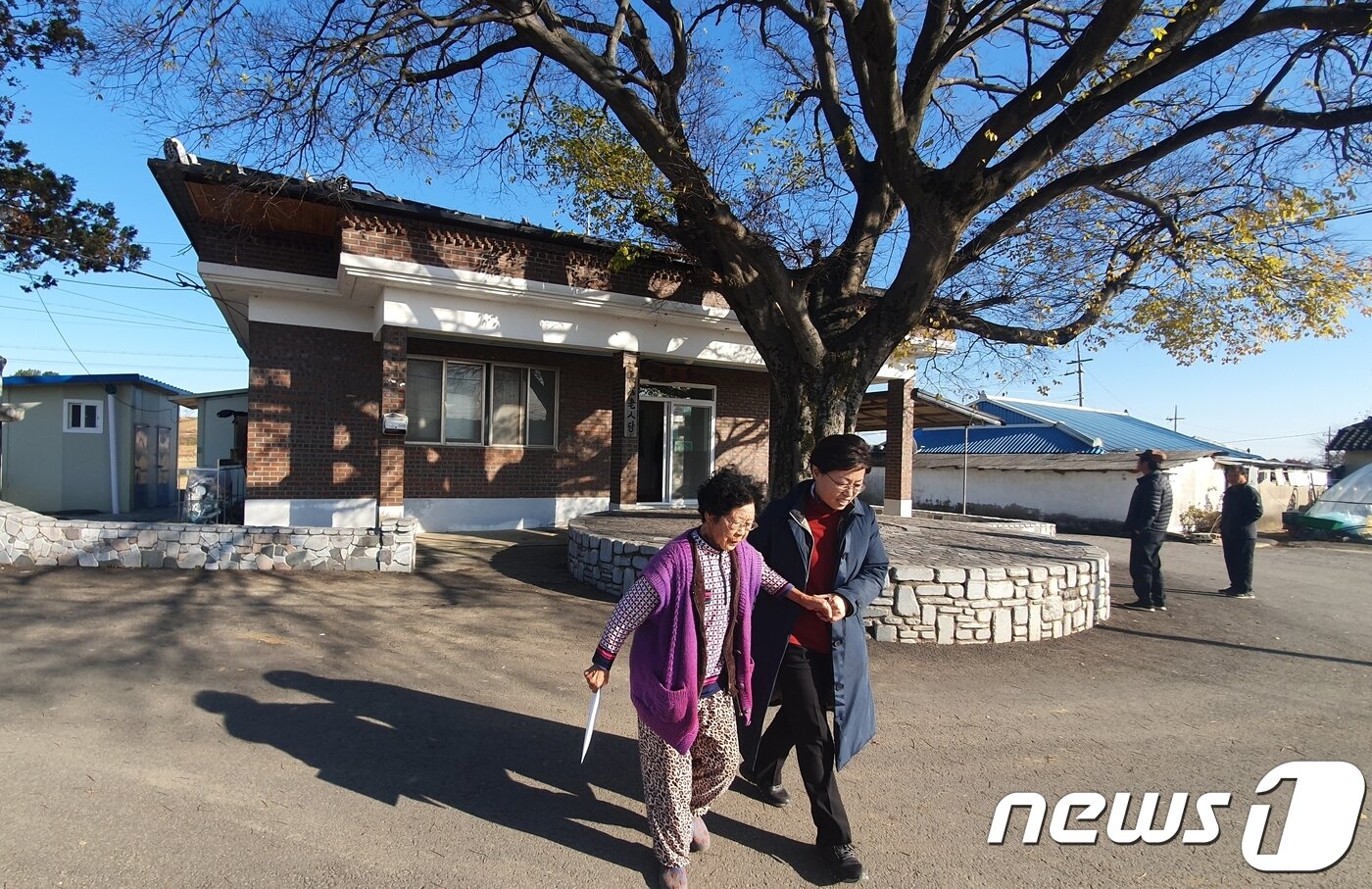 본문 이미지 - 지난 20일  익산 장점마을 주민들이 마을회관에서 건강검진을 받은 뒤 익산시보건소 직원의 부축을 받고 귀가하고 있다. 2019.11.22 /뉴스1