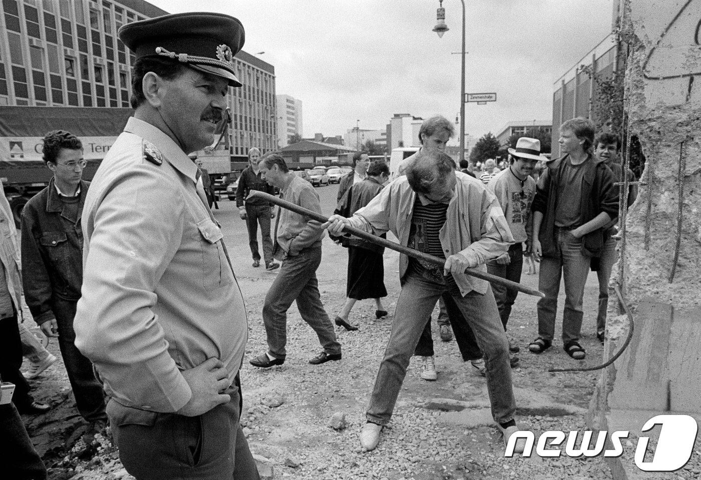 본문 이미지 - 베를린 장벽을 부수는 독일 시민들과 그것을 지켜보는 동독 경찰 <자료 사진> ⓒ 로이터=뉴스1