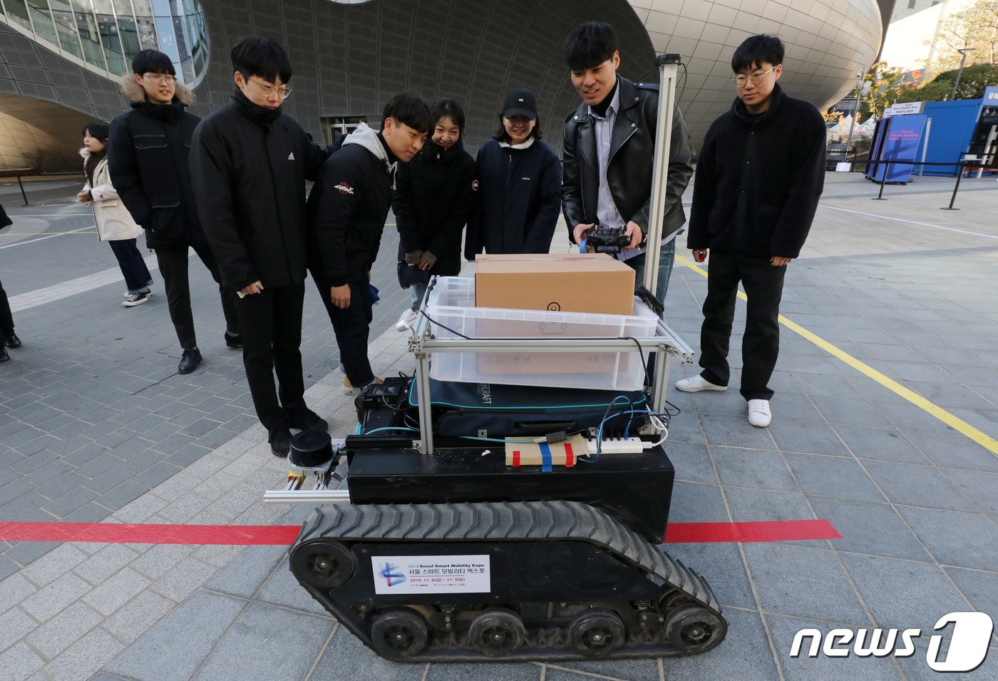 본문 이미지 - '2019 서울 스마트모빌리티 엑스포'를 찾은 시민들이 자율주행 로봇택배 시연을 보고 있다. 2019.11.8/뉴스1 ⓒ News1 박세연 기자