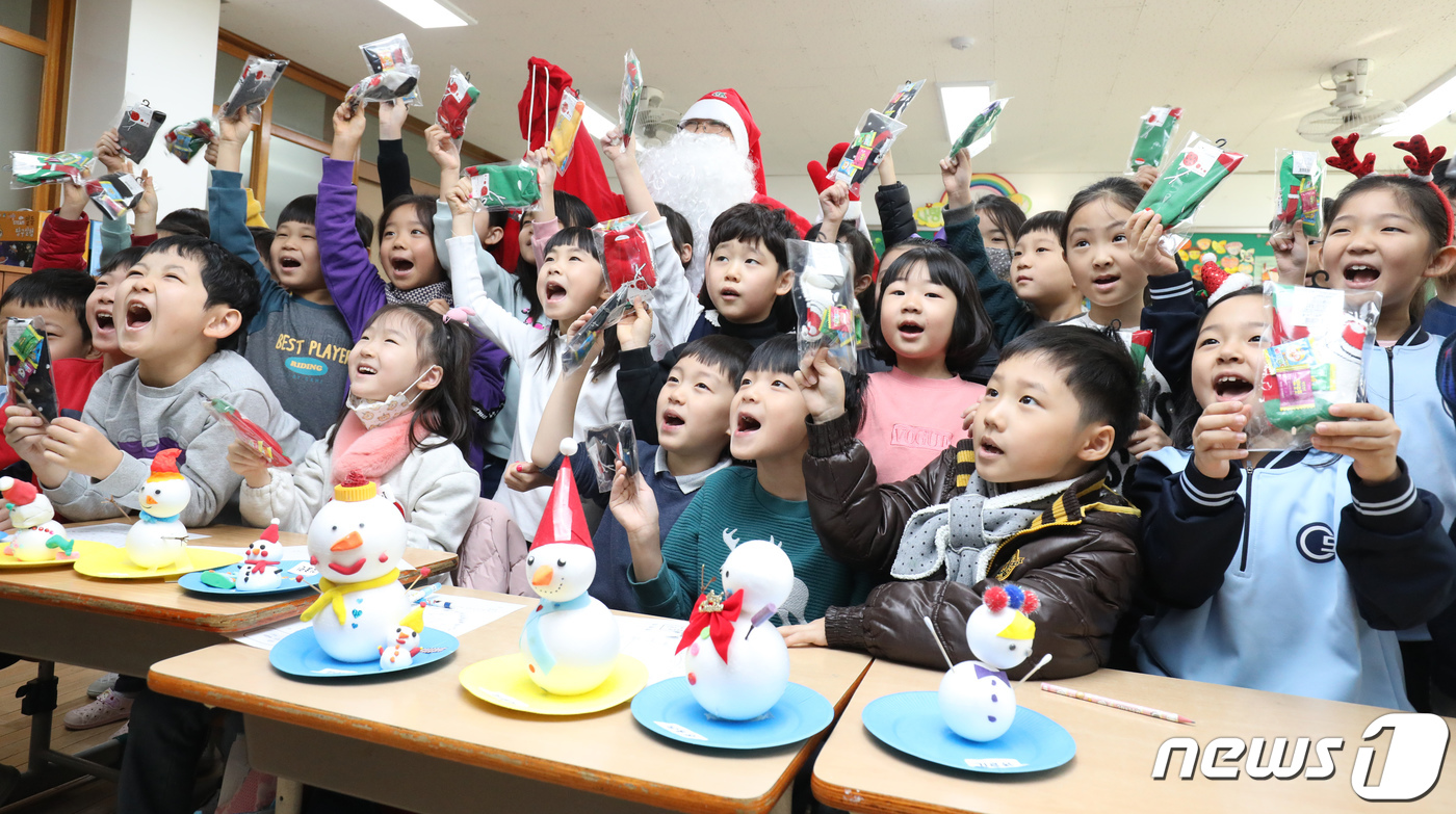 (대구=뉴스1) 공정식 기자 = 크리스마스를 하루 앞둔 24일 대구 수성구 범어동 동도초등학교 1학년 교실에서 방학식을 마친 학생들이 산타가 나눠준 선물을 들고 메리 크리스마스를 …