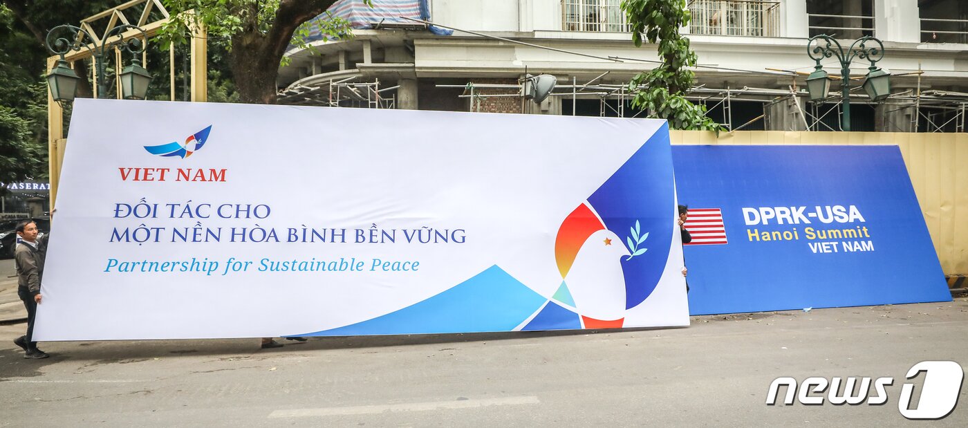 본문 이미지 - 제2차 북미 정상회담을 닷새 앞둔 22일 오전 정상회담 장소로 유력한 베트남 하노이 소피텔 레전드 메트로폴 하노이 호텔 앞에서 베트남 작업자들이 북미 정상회담 공식 로고와 환영 메세지가 담긴 대형 현수막을 옮기고 있다. 현수막 하단에 '지속가능한 평화를 위한 파트너십' 이라는 문구가 적혀 있다. 2019.2.22/뉴스1 ⓒ News1 성동훈 기자