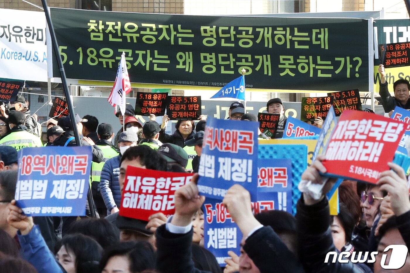 본문 이미지 - 23일 오후 서울 종로구 청계광장을 출발한 '5.18 민주화운동 왜곡 모독 망언 3인 국회의원 퇴출·5.18 학살·역사왜곡 처벌법 제정·자유한국당 규탄 범국민대회' 참가자 행진 대열 뒤로 보수단체가 5.18 유공자 명단 공개를 요구하며 집회를 열고 있다. 2019.2.23/뉴스1 ⓒ News1 민경석 기자