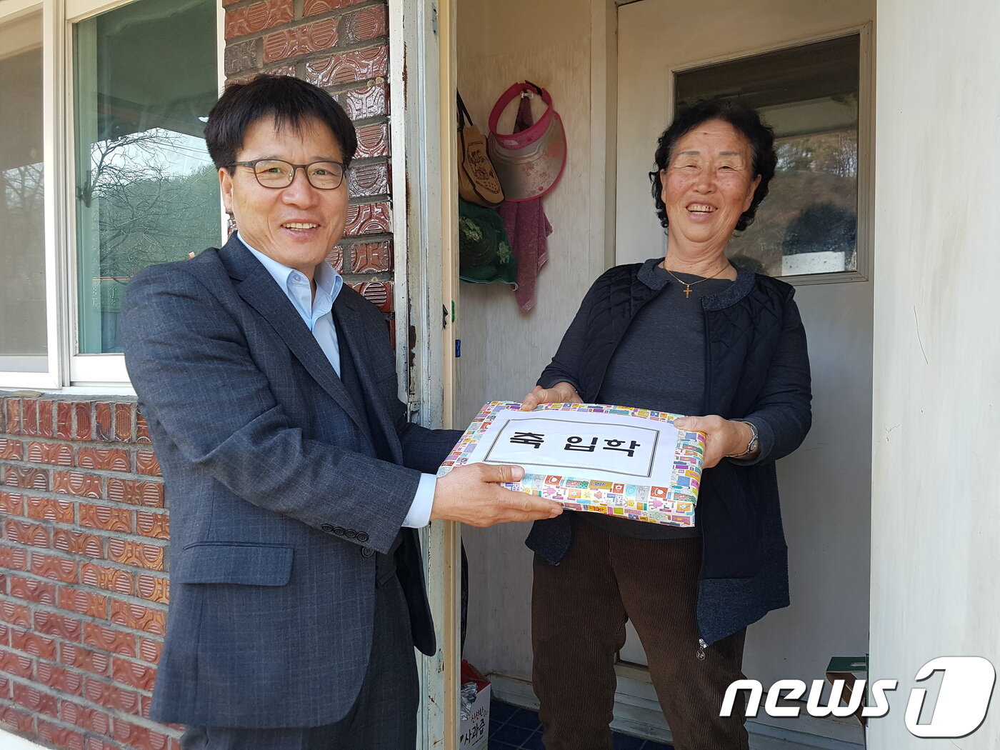본문 이미지 - 지난 11일 충북 보은 회인초등학교에 입학한 김풍자 할머니에게 김상원 회인면장이 학용품을 전달하며 격려하고 있다.&#40;보은군청 제공&#41;.2019.03.12.ⓒ 뉴스1