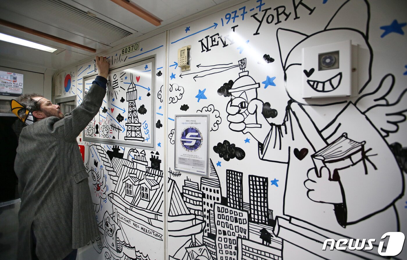 본문 이미지 - 거리 예술가 토마 뷔유가 12일 오후 서울 응암순환 6호선 지하철 객차 안에서 그의 대표 캐릭터인 '무슈샤 웃는 고양이' 그림을 그리는 행위예술을 하고 있다. 2019.3.12/뉴스1 ⓒ News1 성동훈 기자