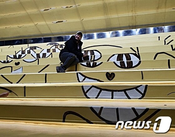 본문 이미지 - 토마 뷔유는 지난 7일 서울 마포구에 있는 KB청춘마루 내 노랑계단 등에 '웃는 고양이'를 그렸다. 사진 KB국민은행 제공 ⓒ 뉴스1